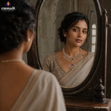 Woman in cream saree looking into an antique mirror wearing a silver paisley necklace with pink stone and pearl drops