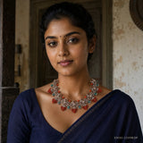 Woman in navy saree wearing a Victorian antique-finish necklace with coral bead clusters and green stone accents