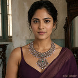 Woman wearing a Victorian style green necklace with layered antique finish design over a maroon saree