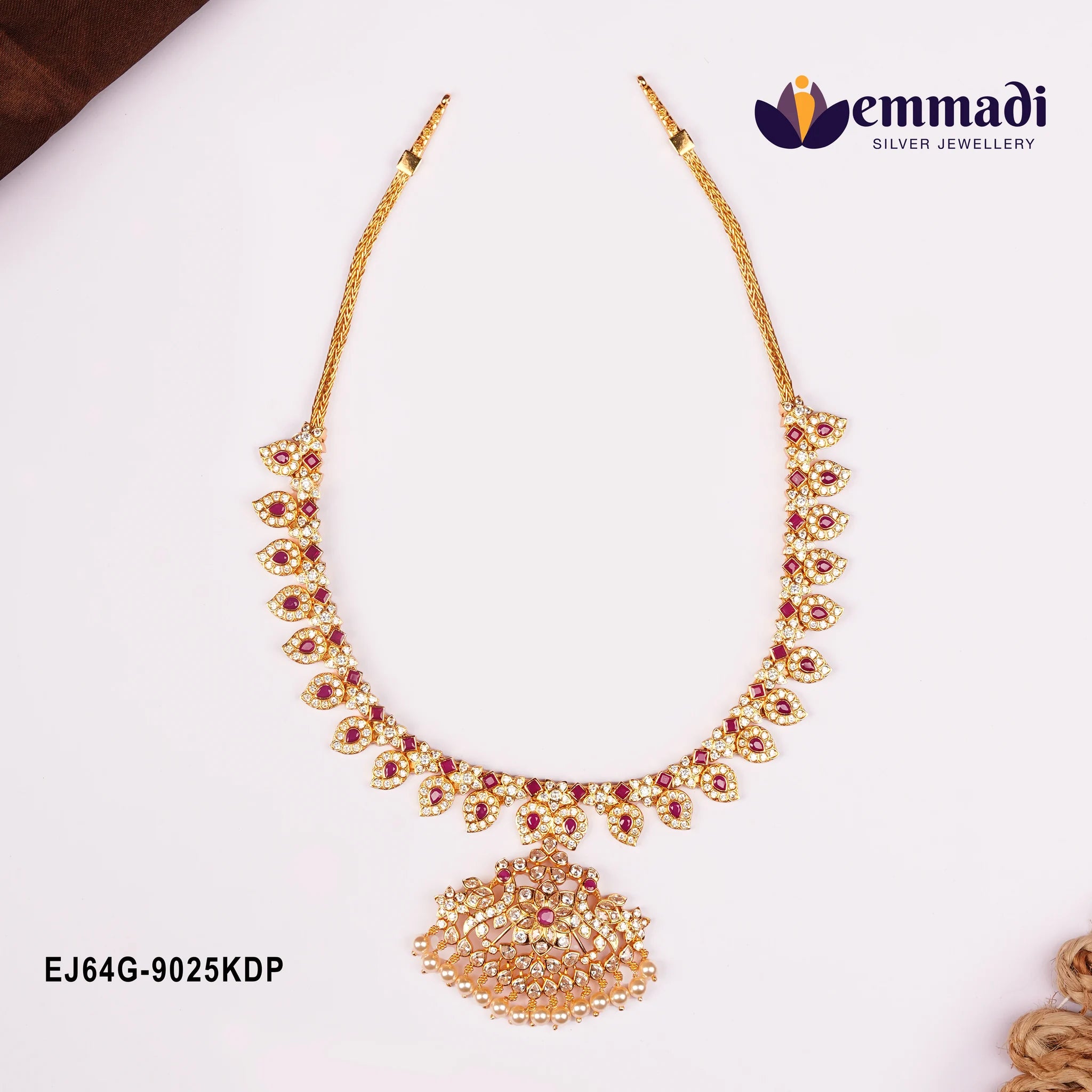 Long necklace laid flat on white background showing woven chain and leaf shaped pink stone motifs