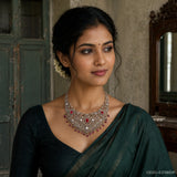 Woman in dark green saree wearing an ornate Victorian-style red and white stone necklace