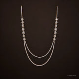 Ira Ethika white long necklace on dark brown background showing bezel-set stones and double-strand drape