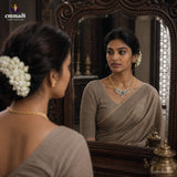 Woman in beige saree reflected in an ornate wooden mirror, wearing a gold-tone CZ necklace with green stones