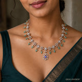 Close-up of neckline showing Victorian necklace with blue centre stone, pearl clusters and green drops