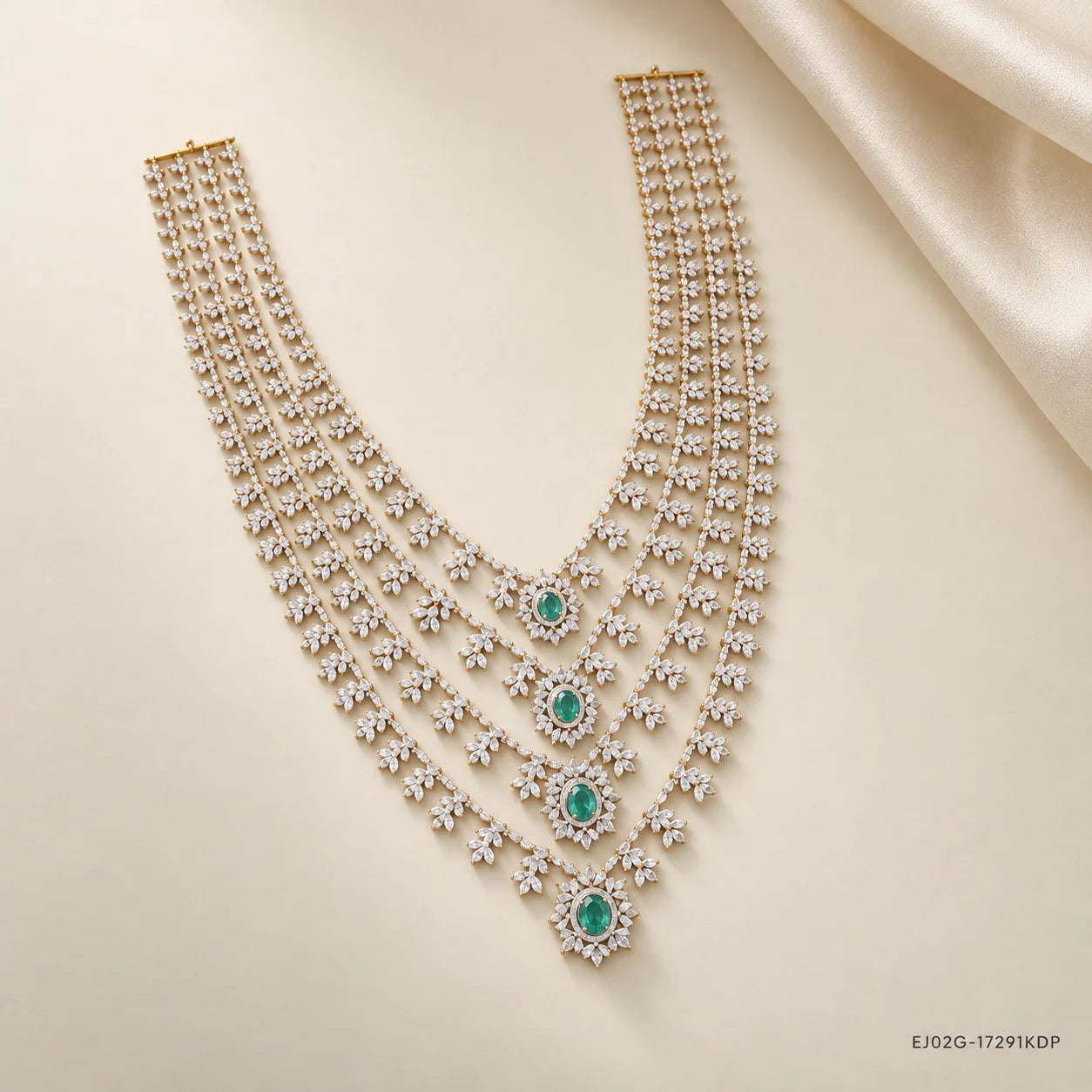Layered bridal necklace with cubic zirconia clusters and green stone drops on cream fabric