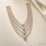Layered bridal necklace with cubic zirconia clusters and green stone drops on cream fabric