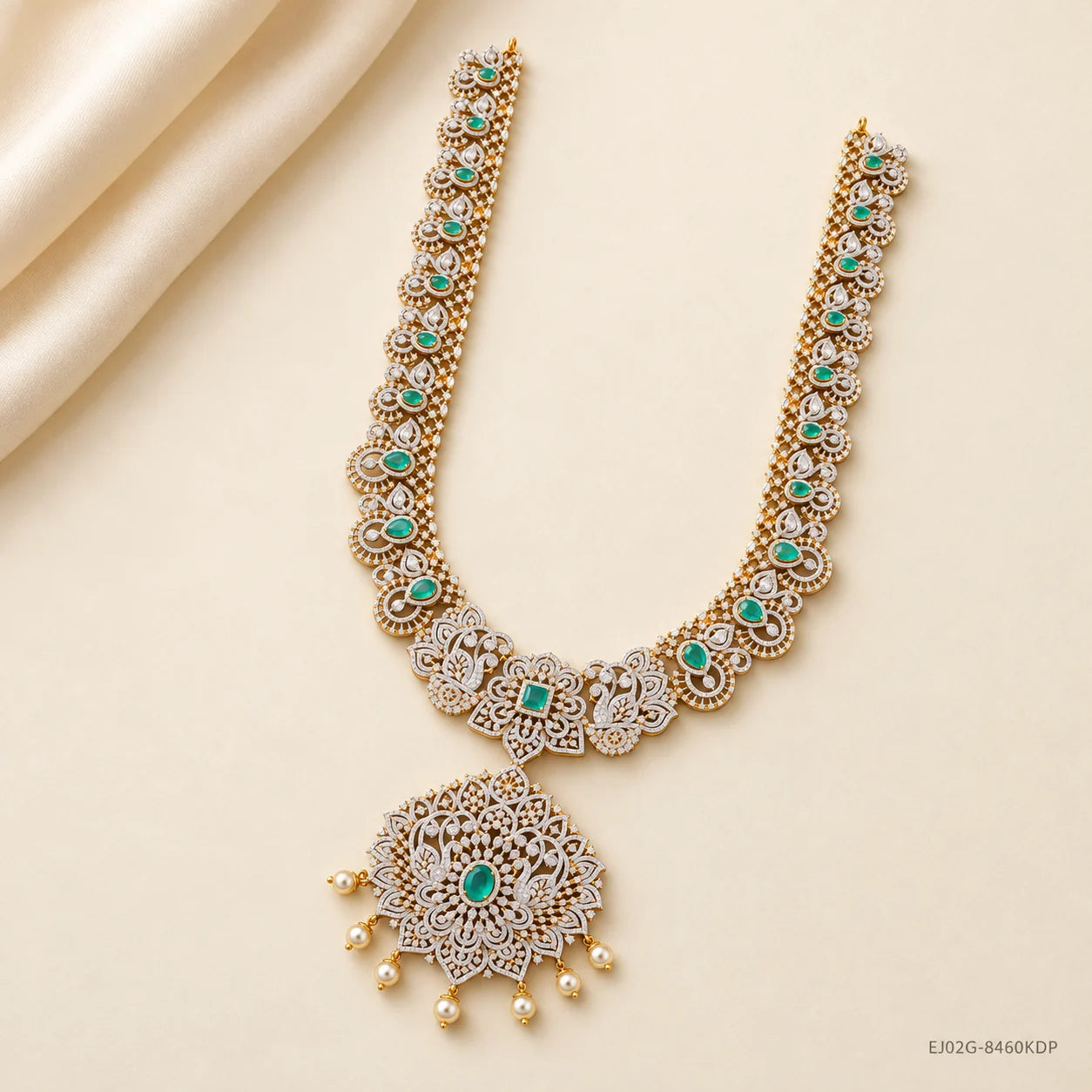 Green stone long necklace with pave work and pearl drops displayed on cream fabric
