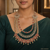 Close-up of red and white CZ long necklace with circular pendants and pearl drops on green blouse