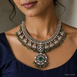 Close-up of the necklace on the neck showing elephant motifs and central green stone pendant