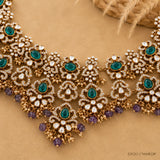 Victorian necklace laid on fabric showing antique finish, green stones and amethyst bead tassels