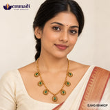Woman in a cream saree wearing a gold-tone beaded necklace with green stone teardrop pendants