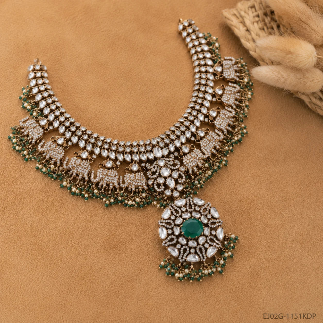 Necklace laid on tan fabric beside dried flowers, showing elephant row and floral pendant