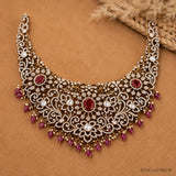 Flat lay of Victorian necklace on tan fabric showing floral filigree and red stone accents