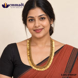 Woman wearing the nakshi long necklace with coin motifs over a rust coloured saree