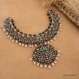 Victorian green necklace laid flat on beige fabric, showing intricate antique finish scrollwork and pendant
