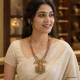 Woman wearing the pink stone long necklace with ornate pendant over a cream saree blouse