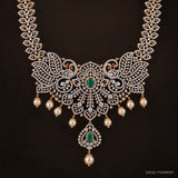Close-up of the pendant showing twin peacock motifs, central green stone and hanging pearls
