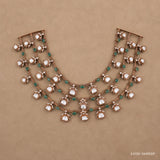 Flat lay of the three-tier Victorian necklace with white stone drops and green beads on a beige backdrop