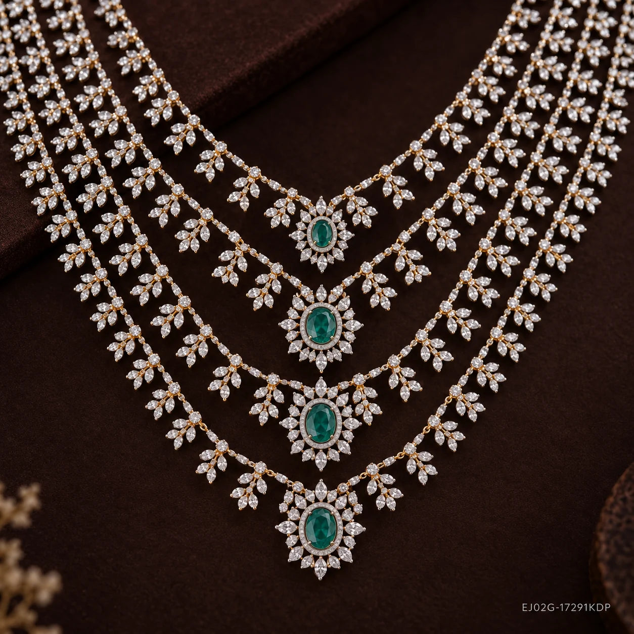 Close-up of graduated necklace strands showing floral cubic zirconia work and oval green stones