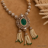 Flat lay of the Ira Victorian green necklace on brown fabric with dried wheat stalks, showing tassel detail