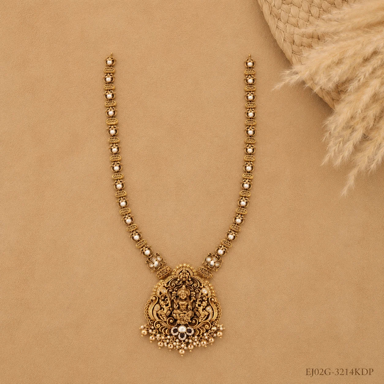 Full flat-lay view of the long necklace on beige fabric showing the beaded chain and pendant with drops