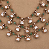 Close-up of the necklace's central pendant cluster showing white stones, green beads and floral motifs