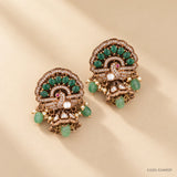 Victorian buttalu earrings with jhumki style base and green stone dangles, on beige background with soft shadow