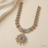 Full view of green stone long necklace with scalloped border laid on cream fabric