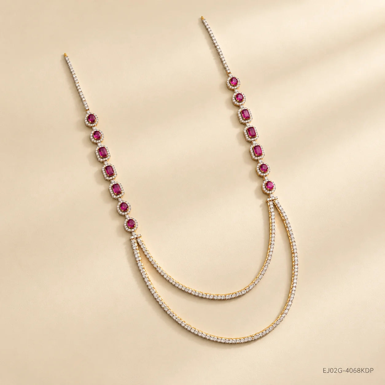 Angled view of the long necklace showing pink stones, pave chain and loop detail, on beige surface