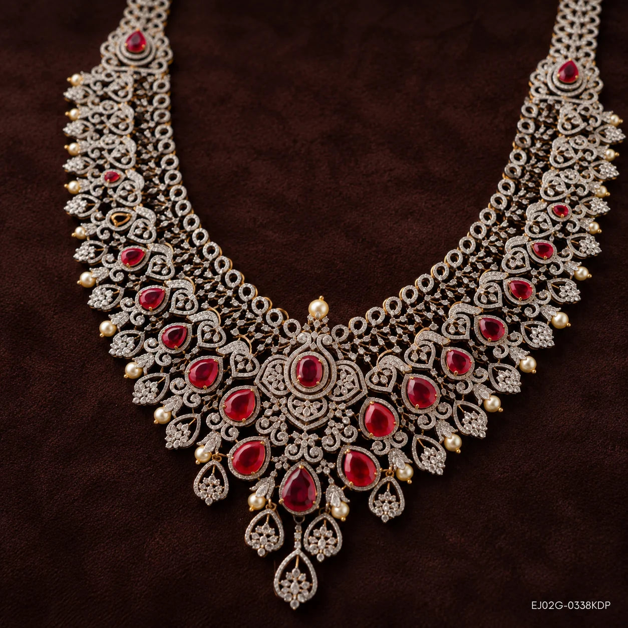 Long necklace with pave CZ scrollwork, pear-shaped red stones and pearl drops on dark brown fabric
