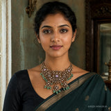 Woman in a black saree wearing an antique-finish choker necklace with lavender stones and green tassel drops