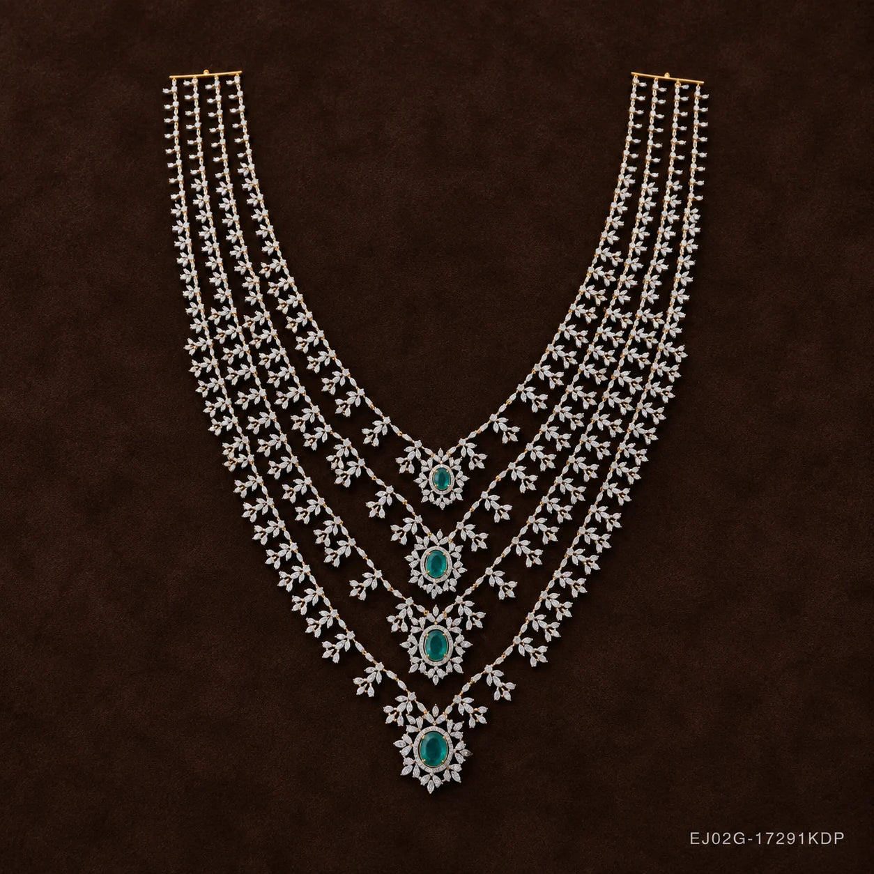 Four-layer silver necklace with green stone pendants laid flat on dark brown fabric