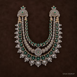 Three-tier green and white pave long necklace with swan pendants, shown on a dark brown background