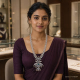 Woman in a purple saree wearing a long white CZ necklace with pearl drops and a peacock pendant