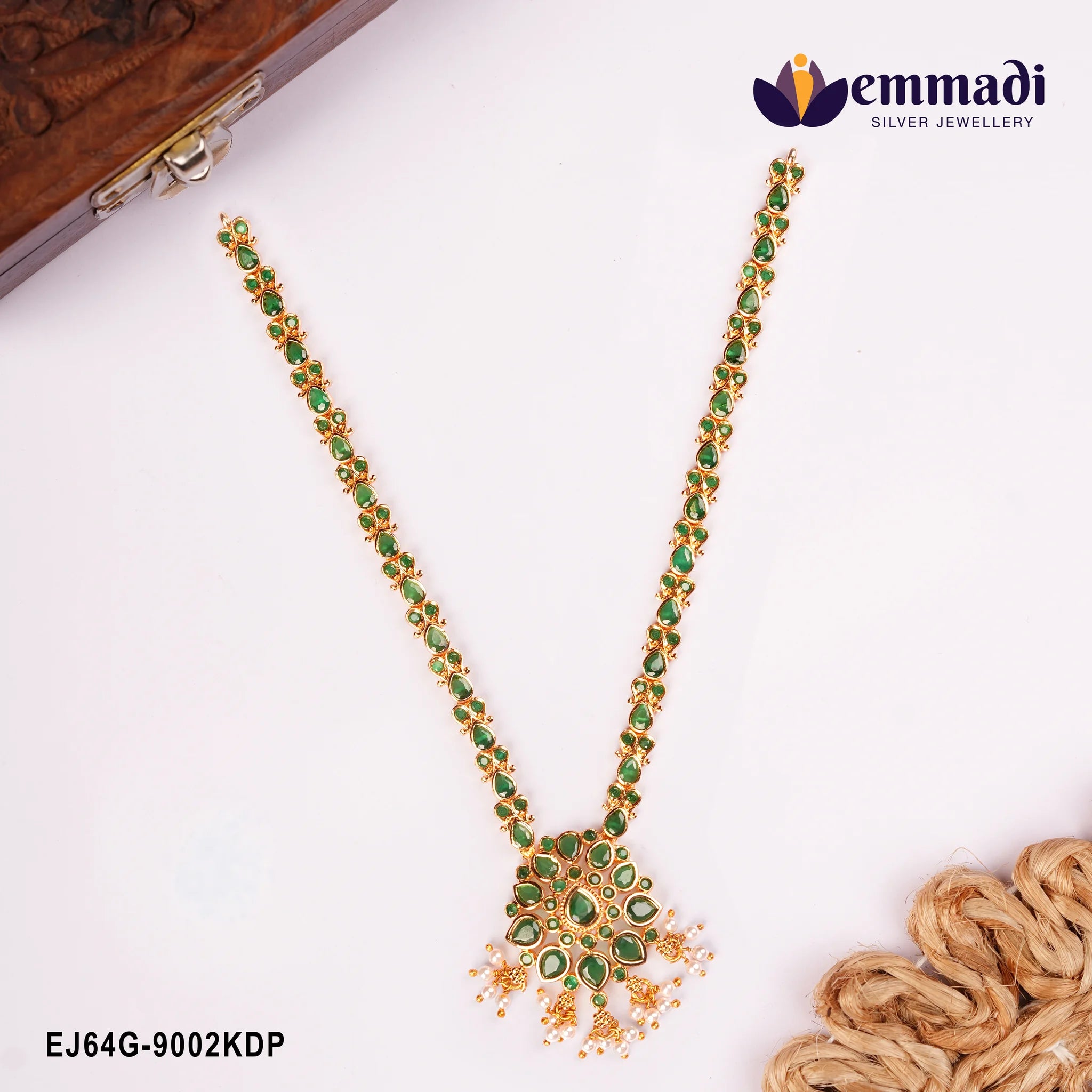 Long green stone necklace with floral pendant and pearl drops displayed beside a wooden box