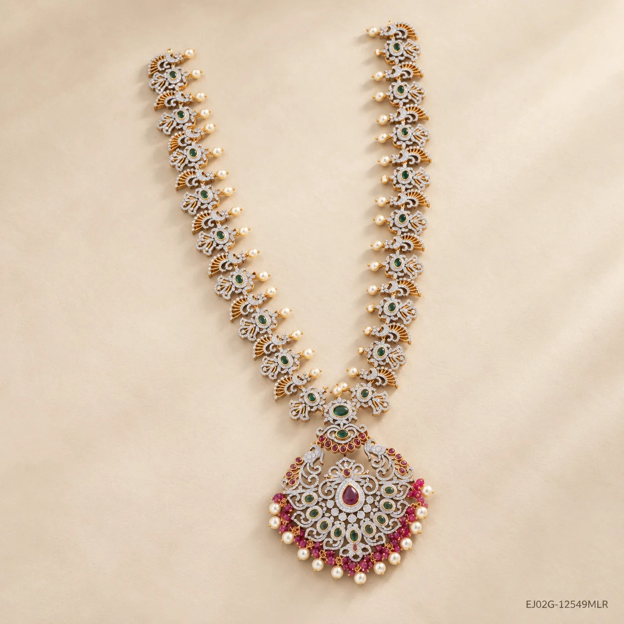 Green long necklace with pearl drops and pink stone pendant laid flat on beige background