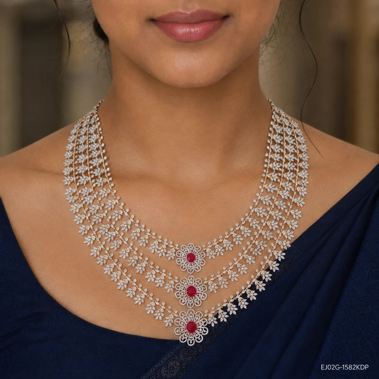 Close-up of the layered necklace on the neckline showing floral pave work and three red stone medallions