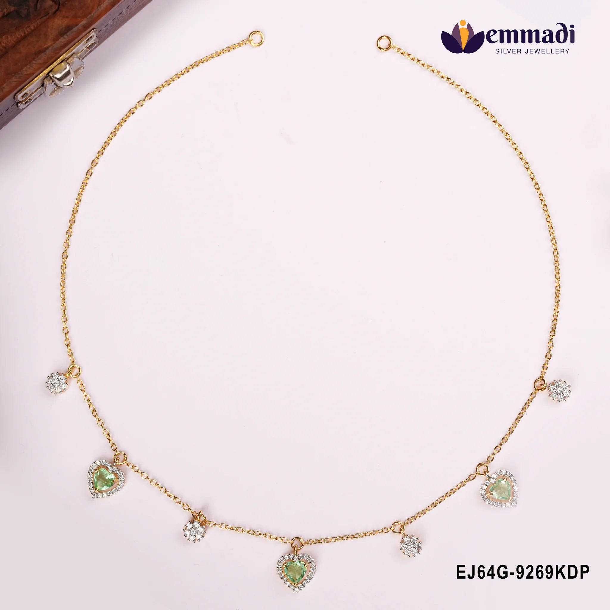 Necklace laid open showing both clasp ends with green heart pendants and round white stone charms