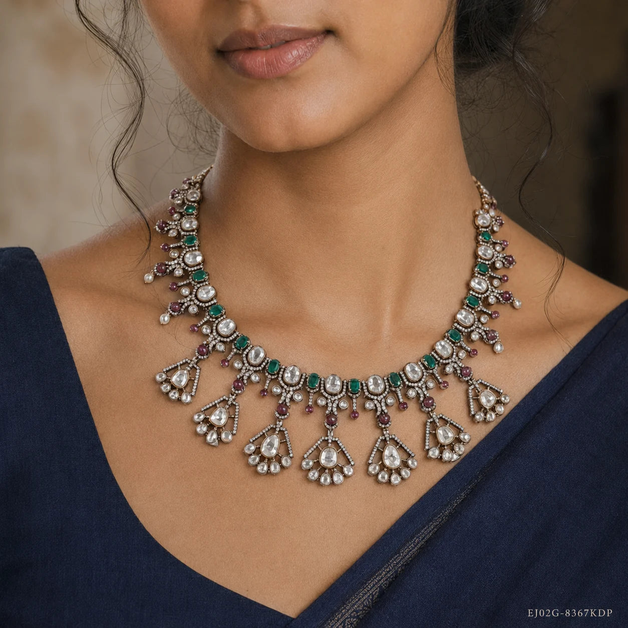 Close up of the neckline showing the necklace's fan shaped drops with green and clear stone detailing
