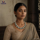 Close up portrait of a woman wearing a green and white floral cubic zirconia necklace with an embroidered beige saree