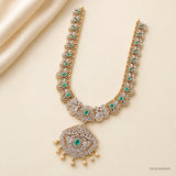 Green stone long necklace with pave work and pearl drops displayed on cream fabric