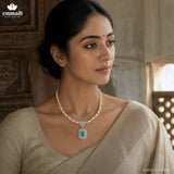 Close-up portrait of a woman wearing a pearl strand necklace with CZ florets and a green stone pendant