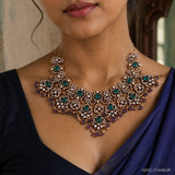 Close-up of the green stone Victorian necklace resting on the neckline showing floral motifs