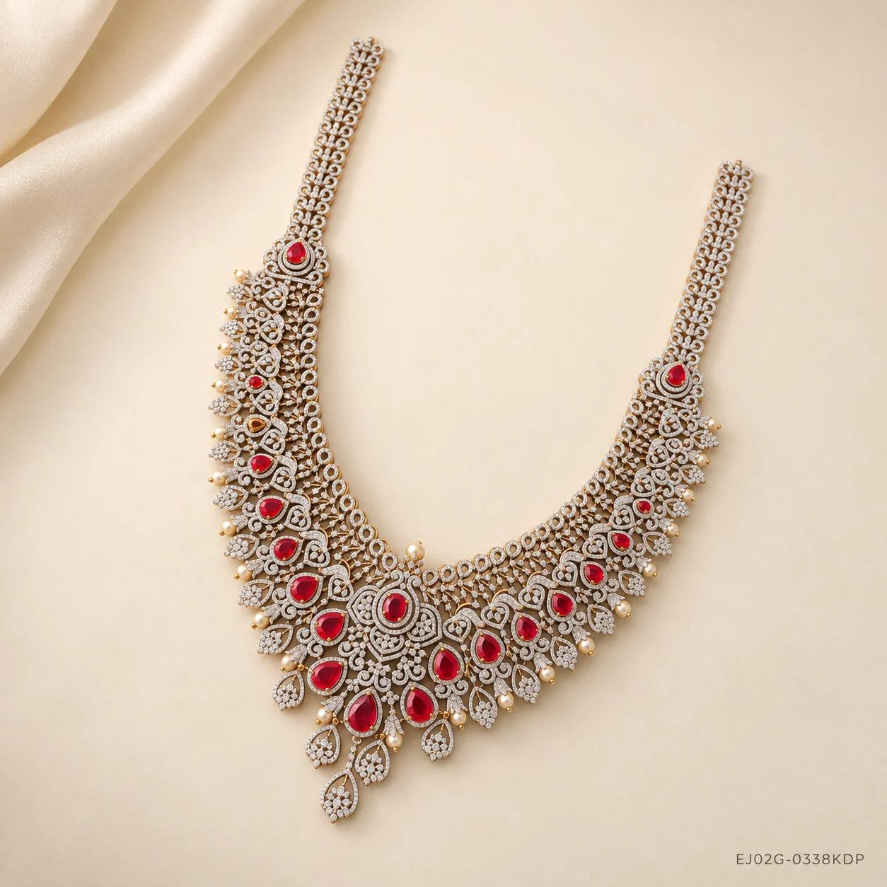 Full view of long necklace laid on cream fabric, showing two long CZ straps and red stone clusters