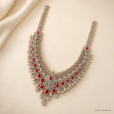 Full view of long necklace laid on cream fabric, showing two long CZ straps and red stone clusters