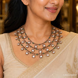 Close-up of the layered necklace on the neckline showing white stone drops and green bead accents