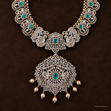 Close-up of floral pendant with peacock motifs, green stone centre and pearl drops