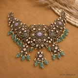 Flat lay of the Victorian choker necklace with lavender cabochons and green stone drops on tan fabric