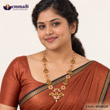 Woman wearing an antique gold nakshi necklace with pink stones and peacock pendant over an orange saree