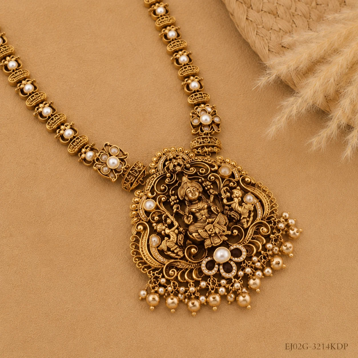 Close-up of the necklace pendant showing a carved deity figure flanked by peacock motifs with pearl drops